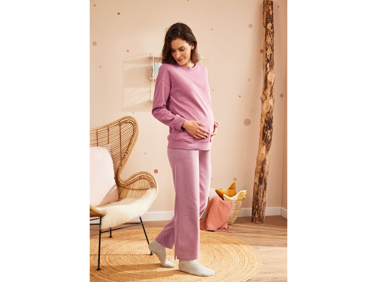 Une femme enceinte portant un survêtement rose et des chaussettes blanches.