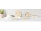 Vaisselle élégante en céramique beige et blanche sur fond clair.