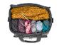 Un sac gris avec de la laine, des aiguilles à tricoter et des tricots.