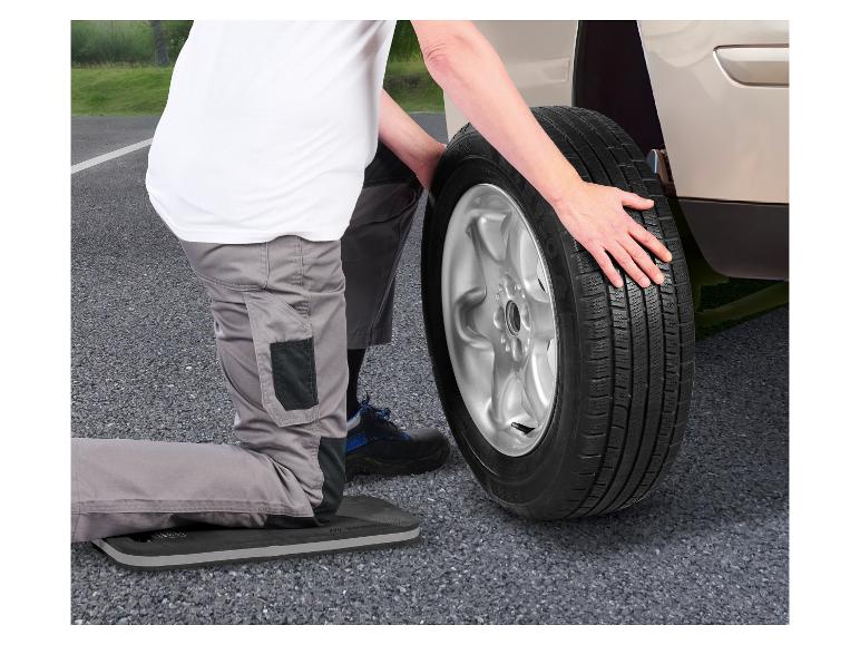 Personne changeant un pneu de voiture avec un coussin de genoux.