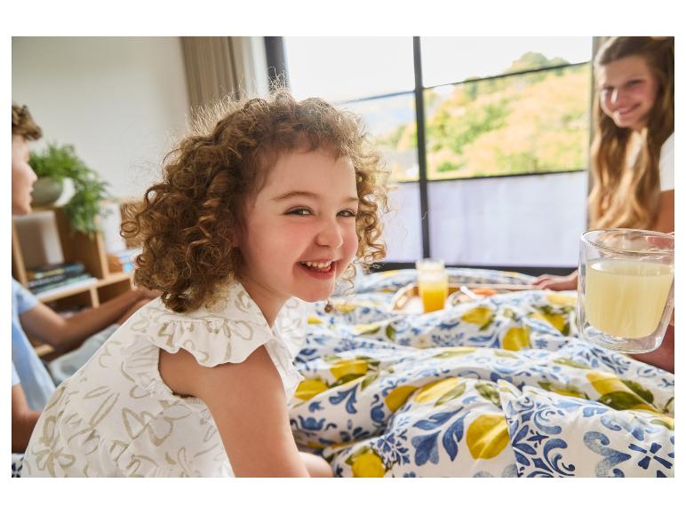 Enfants au petit-déjeuner au lit avec un linge de lit citron.