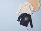 Deux t-shirts à manches longues pour enfants, un beige avec l'inscription 'Make Some Noise' et un bleu marine avec un imprimé de tigre.