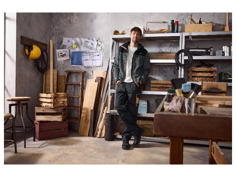 Homme en tenue de travail Parkside dans un atelier avec outils et bois.