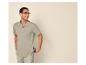 Homme avec des lunettes, polo vert clair et short beige, souriant et regardant de côté.