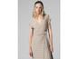 Une femme porte une robe beige à manches courtes.