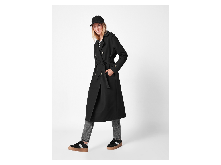 Modèle portant un long manteau noir et des baskets.