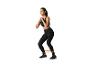 Femme en tenue de sport noire faisant des squats avec une bande de résistance.