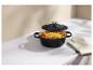 Cocotte en fonte noire avec poulet rôti et légumes, à côté d'une manique.