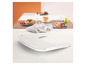 Un plateau blanc avec un donut, un pamplemousse et des tomates cerises sur une table en bois.