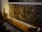 Guirlande lumineuse stalactite dans une fenêtre avec décor en bois et cadeaux, créant une ambiance chaleureuse.