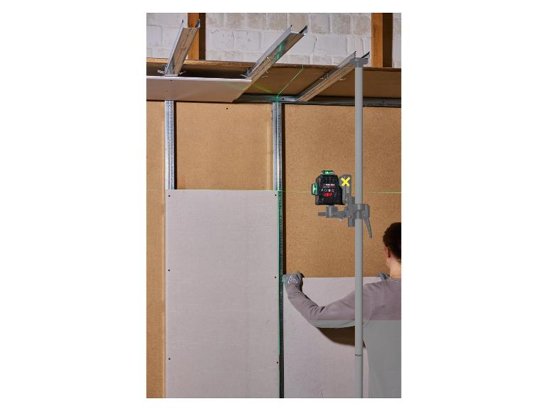 Un niveau laser sur un poteau aide un ouvrier à installer des panneaux de plâtre.