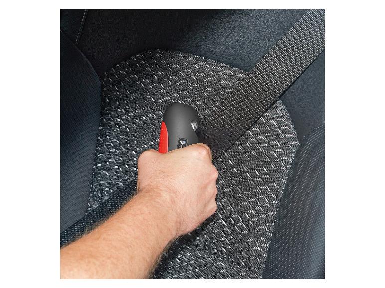 Un homme tient un coupe-ceinture noir avec un bouton rouge dans une voiture.