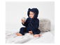 Bébé adorable dans une combinaison en peluche bleu marine jouant avec une balle.