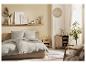 Chambre à coucher avec linge de lit gris clair et meubles en bois naturel.