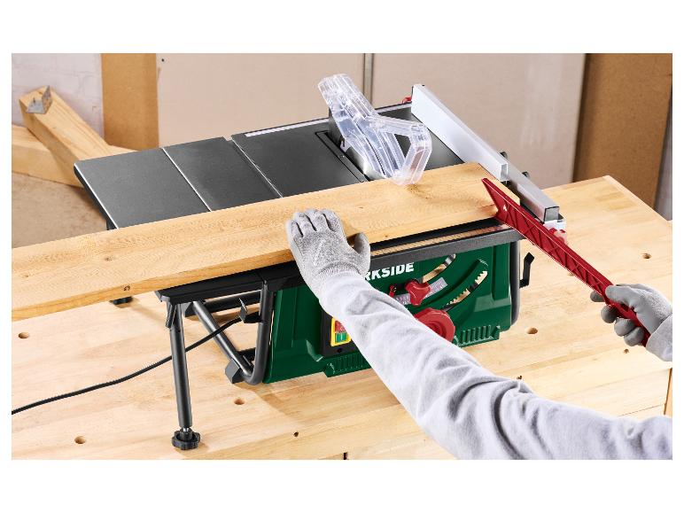Scie sur table coupant une planche de bois, avec des mains gantées et un poussoir