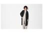 Une femme porte un long pull en maille noir avec un pantalon beige.