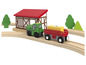 Un tracteur vert avec une remorque rouge sur des rails en bois.