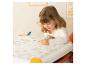 Petite fille coloriant un livre sur une table avec un marqueur vert.