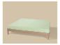 Lit en bois avec matelas vert clair sur fond beige.
