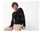 Modèle masculin portant un pull noir et un pantalon en velours beige.
