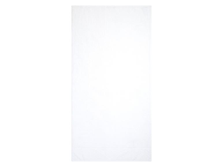 Une serviette de bain blanche avec un motif brodé.