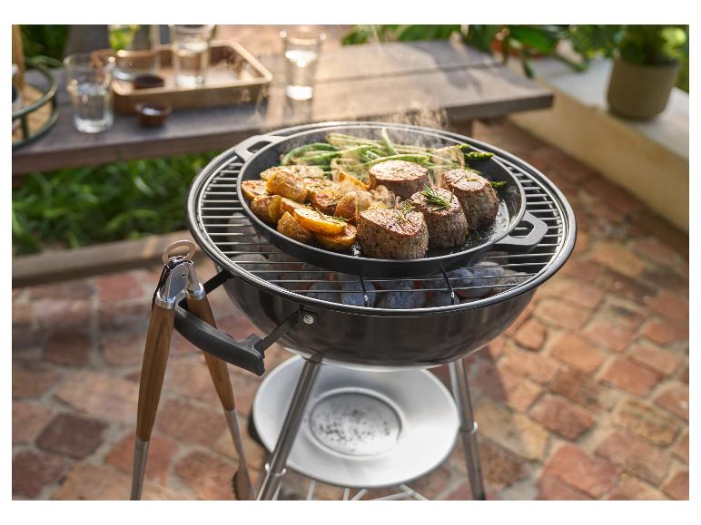 Barbecue avec une poêle de viande grillée, pommes de terre et haricots verts, avec des pinces à côté.