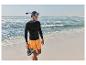 Homme en t-shirt noir, short orange, masque de plongée et chaussures aquatiques sur la plage.