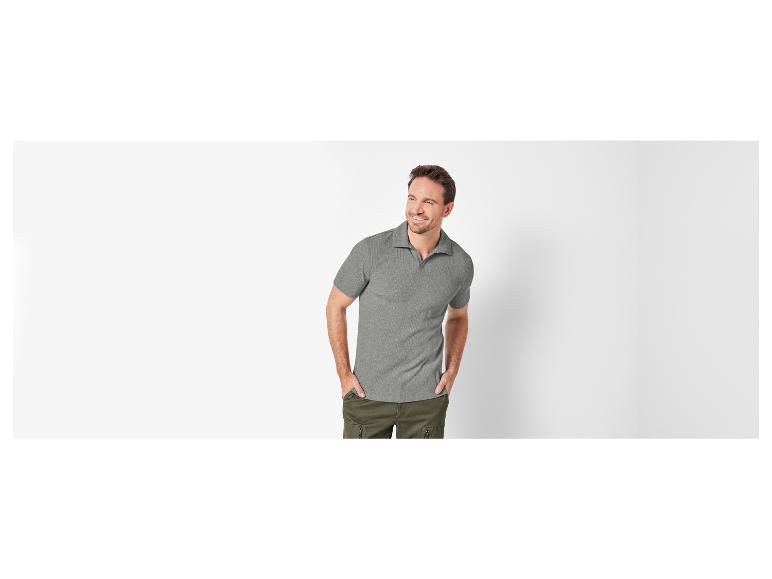 Un homme porte un polo gris et un pantalon cargo vert.