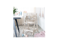 Chaise haute en bois clair avec plateau et harnais, à côté d'une table avec vaisselle pour enfants.