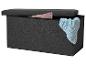 Banc de rangement gris foncé avec une couverture tricotée bleu clair et un coussin rose à l'intérieur.
