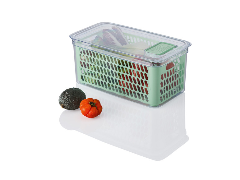 Une boîte de rangement en plastique verte avec un couvercle, remplie de légumes.