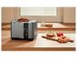 Grille-pain avec pain complet, bagels au fromage frais et tomates sur un comptoir en bois.