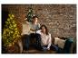 Un couple en pyjama de Noël sur le canapé devant le sapin de Noël.