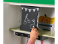 Main d'enfant dessinant à la craie sur un tableau noir d'une cuisine en jouet.