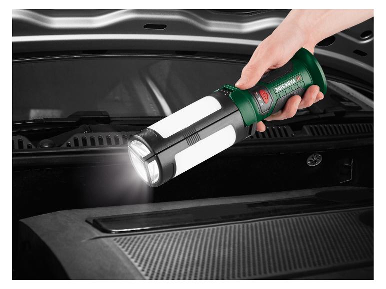 Une main tient une lampe de poche pliable éclairant le compartiment moteur d'une voiture.