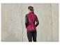 Une femme porte un gilet rouge foncé et un legging noir.