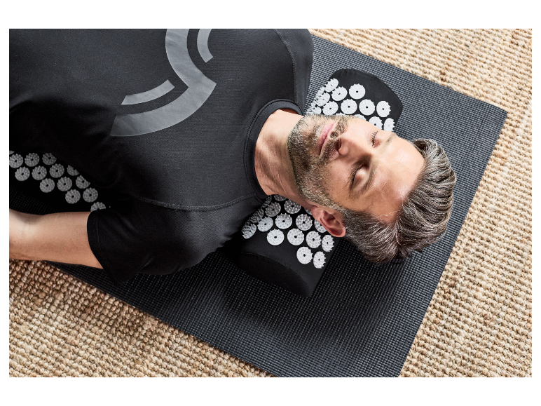 Un homme se détend sur un tapis d'acupression.