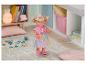 Poupée BABY born en jupe tutu arc-en-ciel et t-shirt rose dans une chambre d'enfant.
