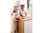 Deux enfants en tabliers et mitaines de cuisine de Noël cuisinent dans la cuisine.
