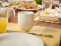 Table de petit-déjeuner avec une tasse blanche, du jus d'orange et des pâtisseries sur une table en bois.