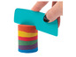 Une main utilise une spatule bleue Play-Doh pour modeler du sable arc-en-ciel.