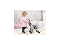 Un bambin joue avec une poussette pour poupée rose de Bayer Design.