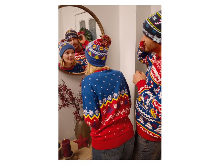 Couple en pulls et bonnets de Noël, avec un sapin de Noël dans le miroir.
