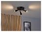 Un luminaire de plafond noir avec trois lumières pointées sur un mur en bois.