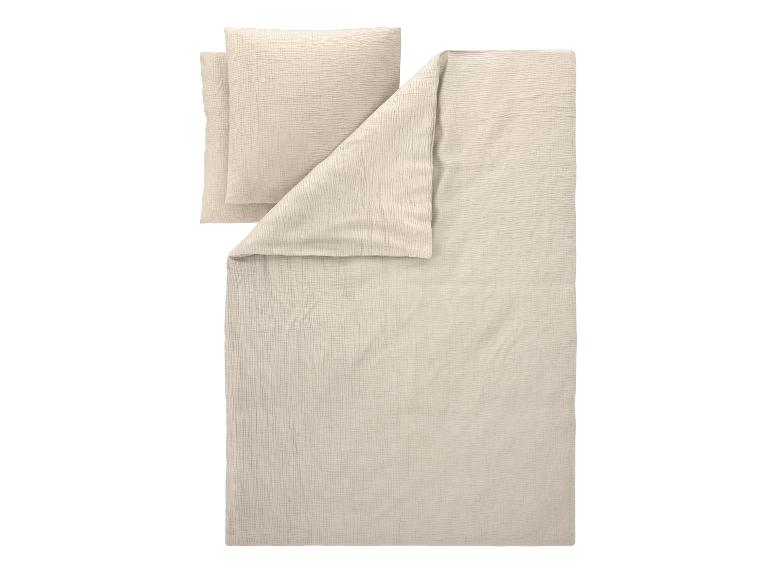 Parure de lit en crêpe beige avec deux taies d'oreiller et une housse de couette.