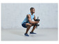 Un homme en vêtements de sport fait des squats avec des haltères.
