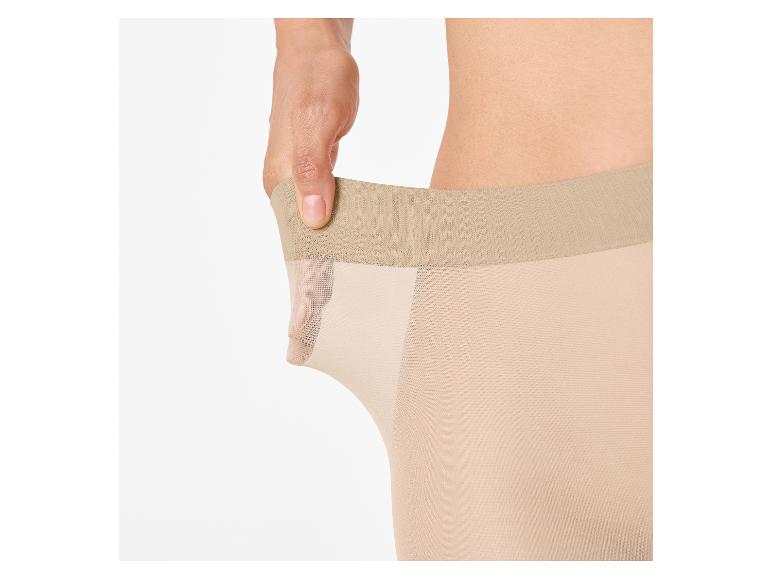 Main étirant des collants couleur chair, montrant leur élasticité.