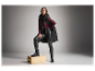 Modèle portant un gilet matelassé noir, un pull bordeaux et un pantalon en cuir.