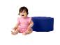 Un bébé en barboteuse rose à motif soleil assis à côté d'un pouf bleu.