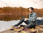 Un homme pêche avec une canne à pêche et s'assoit sur une couverture au bord d'un lac.